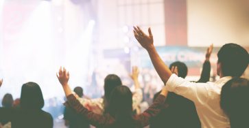 churchgoers raise hands in service