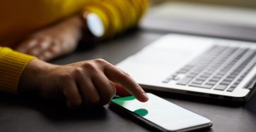Women’s hands using smartphone laptop computer