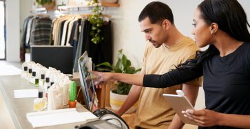 two retail employees work at the register