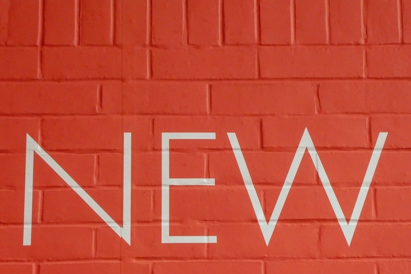 The word new on an orange brick wall